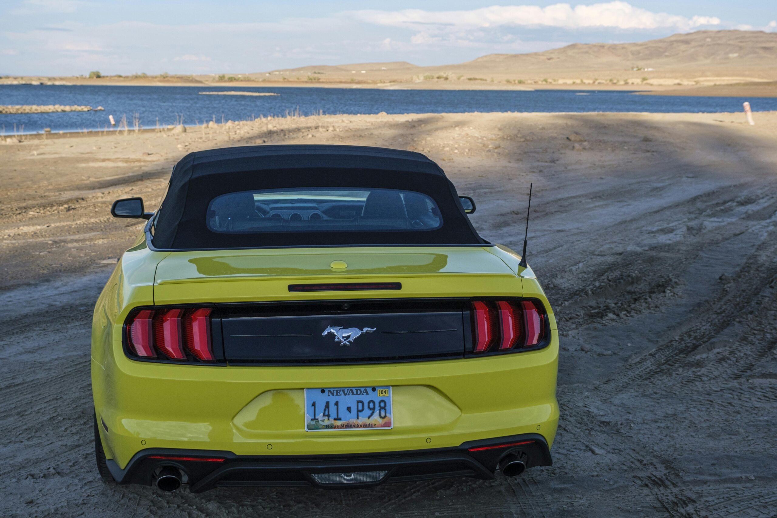 A vibrant yellow Ford Mustang parked by a serene lake in Fallon, Nevada.