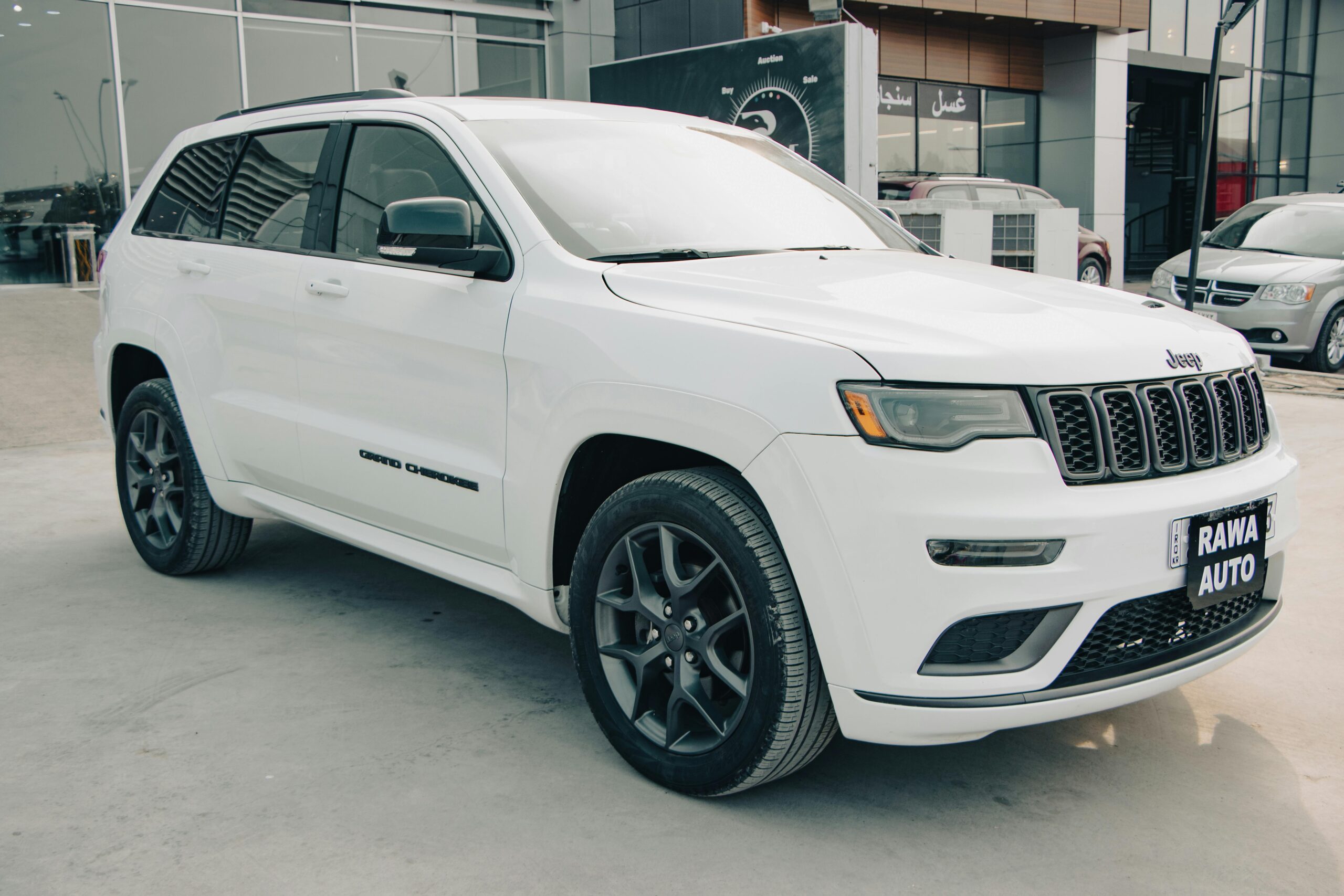 White Jeep SUV parked outdoors at a dealership, showcasing modern automotive design and style.